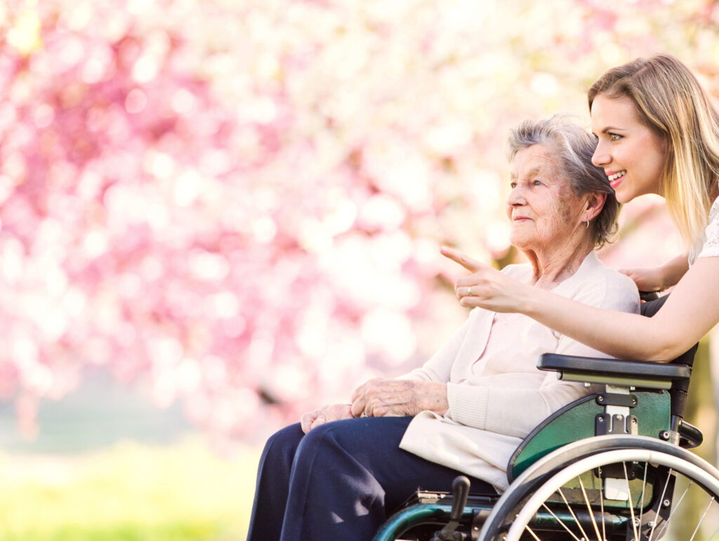 smiling caregiver accompanying elderly woman in a wheelchair