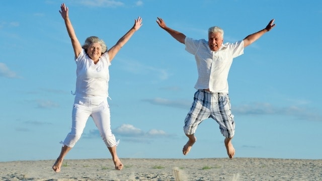 the gift of aging two happy seniors jumping in the air